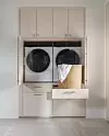 Platsbyggt skåp med tvättmaskin, torktumlare och utdragbar låda med tvättkorg.