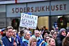 Sjukvårdspersonal utanför Södersjukhuset håller plakat och deltar i en protest.