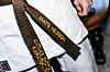 Brunbälte i karate med broderad text på en vit karatedräkt.