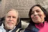 Två personer poserar för en selfie framför en stenmur med inskriven text.