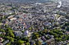 Flygfoto över en tätbebyggd stad med kyrktorn, bostadshus och omgivande grönområden.