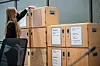 Kvinna i rättssal ordnar stora trälådor märkta som bevismaterial.