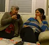 Två kvinnor sitter i en soffa och pratar, en håller en kopp i handen.