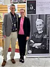 Två personer står framför en bokaffisch med Ulrika Hansson Blomkvist i en lokal.