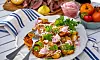 Serveringsfat med grillad potatis, örter och lök på dukat bord utomhus