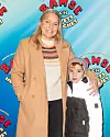 Carina Bergfeldt med sonen Hamilton står framför en blå Bamse-filmvägg och ler mot kameran.