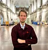 Person står med korslagda armar i Nordiska museets stora hall med högt välvt tak.