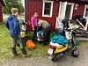 Personer packar gula mopeder med väskor utanför en röd stuga.