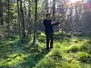 En man står i en solig skog och håller upp händerna som om han förklarar något.