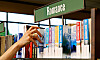 En hand når efter en bok i en biblioteks- eller bokhandels hylla märkt Romance.