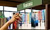 En hand når efter en bok i en biblioteks- eller bokhandels hylla märkt Romance.