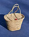 En flätad picknickkorg med handtag står på en blå yta.