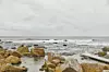 Klippor och en liten brygga vid ett grått hav under mulet väder.