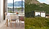 Inifrån en ljus stuga ses ett matbord vid stora fönster mot hav och berg, med en svart träbyggnad utanför.