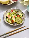 Skalformad assiett med grön sallad, ätpinnar framför.