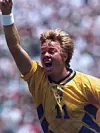 En fotbollsspelare i gul tröja med nummer 11 firar med ena armen i luften.