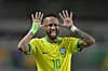 Fotbollsspelare i gul Brasilien-tröja håller upp händerna vid huvudet och räcker ut tungan.