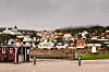 Färgglada hus och bryggor vid en lugn hamn med vatten och grå himmel.