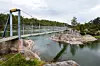En lång hängbro över vatten mellan klippor och små öar i en skärgårdsmiljö.