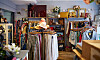 En second hand-butik med klädstänger, hyllor med varor och dekorationer samt träinredning.