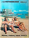 Tre personer sitter och ligger på en sandstrand nära ett hotell och flera båtar ute på vattnet.