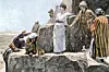 Flera personer i antika och färgstarka kläder står och sitter på stora klippor vid ett stenmonument.