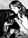 Svartvit bild av en flicka som håller en liten hund i famnen.
