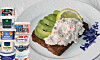 Rågbröd med räkröra och citron på vit tallrik, med staplade yoghurthinkar bredvid.