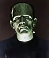 Grönt porträtt av Frankensteins monster med skruvar i halsen mot mörk bakgrund.