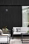 loungegrupp från Bauhaus på altan utanför svartmålat trähus i modern stil