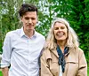 Två personer står sida vid sida utomhus framför träd och buskar i grönt sommarljus.