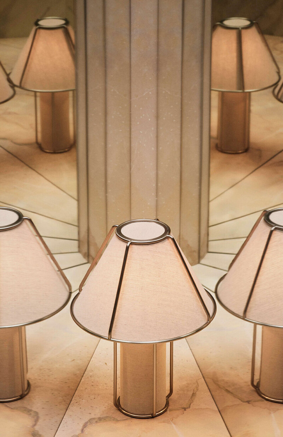 Flera bordslampor med beige skärmar står symmetriskt placerade på ett ljust golv.