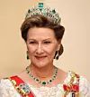 Porträtt av en kvinna med krona, halsband och örhängen med gröna stenar mot beige bakgrund.