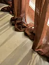 Bruna gardiner i tunn textil vid ett fönster med ljus som faller över ett ljust golv.