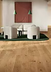 Ljus lounge med två fåtöljer, soffbord, grön matta och väggkonst i ett varmt, minimalistiskt rum.