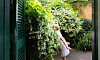 En person står bredvid en vägg med vitblommande jasmin i en trädgård.