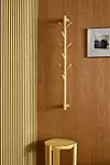 Träpanelad vägg med krokställning, liten pall och en inramad bild i en minimalistisk interiör.