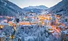 Snöklätt alpsamhälle med upplysta byggnader i en dal omgiven av berg.