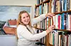 En kvinna tar ut en bok från en bokhylla.