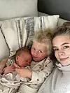 Voksen og to små barn ligger i sofaen og ser mot kameraet