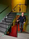 En man står vid en trappa i en inomhusbunker med gröna väggar, röda mattor och metallräcken.