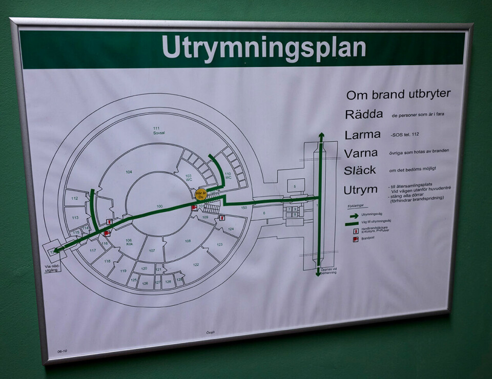En inramad utrymningsplan med kartskiss och brandanvisningar hänger på en vägg.