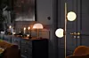 Mörk, stämningsfull interiör med byrå, ljus, spegel och två globlampor i ett modernt rum.