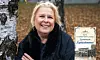 En leende kvinna står vid en björk i en park med höstlöv och håller armarna korsade.
