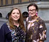Två kvinnor står framför en byggnad med stora bågfönster.