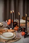 Dukat bord med pumpor, ljus, glas och tallrikar i en höstinspirerad bordsdekoration.