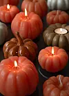 Pumpformade ljuslyktor i orange, brunt och grått med flera tända vekar.