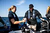 Flera personer står i en liten motorbåt på havet under klar himmel.