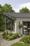 Modernt hus med glasväggar, grått tak och blomsterbädd vid grusgång.