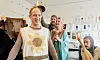 Fyra personer i teaterkostymer står i ett ljust rum med kostymskisser på väggen.